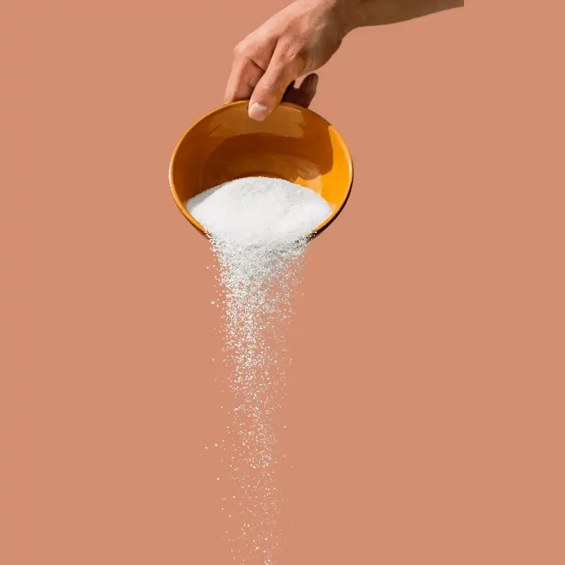 Salt poured mid flow from a hand holding a bowl