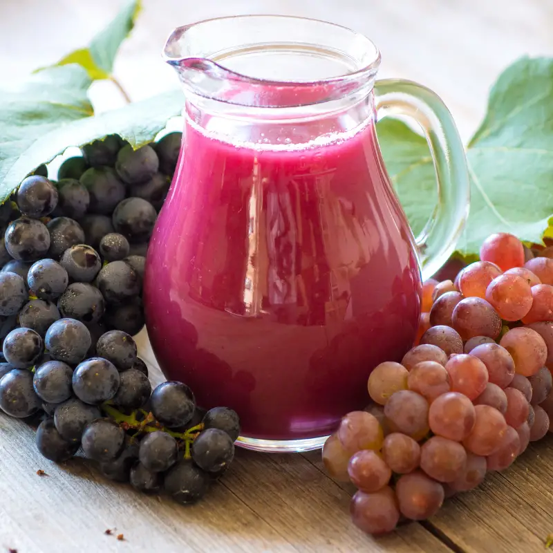 Fresh Grape Juice in a jug with bunches of grapes around it